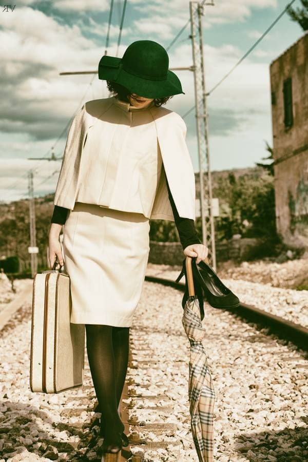 Maira walking along the railway tracks in vintage white suit — a promo editorial