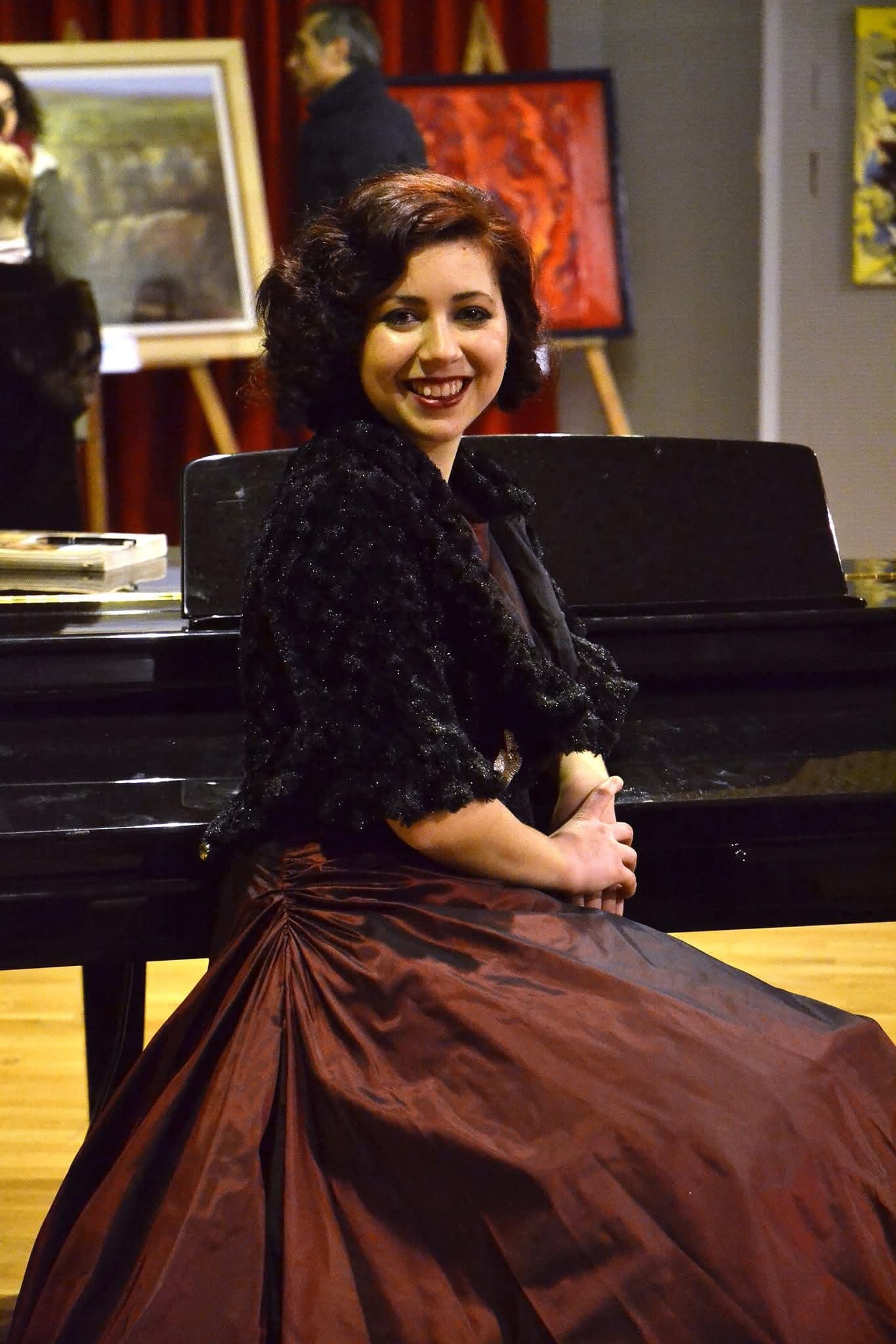 Maira Melchionda in a dark red gown performing live at the piano